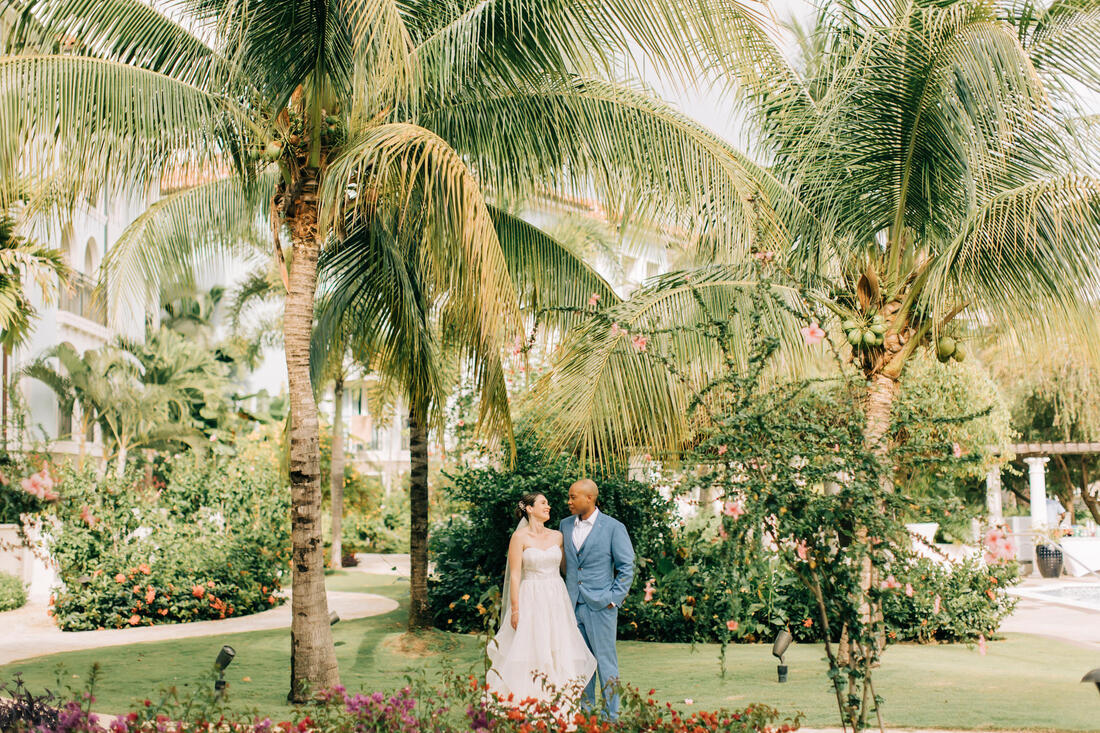 bride and groom standing with palm trees at Sandals South Coast Jamaica 